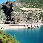 Vue aérienne d'un barrage marocain rempli, symbolisant les réserves d'eau du pays.