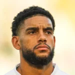 Un joueur de football en tenue d'équipe, avec un doute dans les yeux.