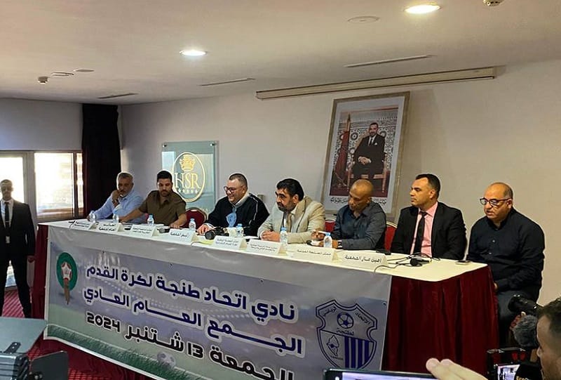 صورة لشعار نادي اتحاد طنجة لكرة القدم، مع خلفية مدينة طنجة في الخلفية.