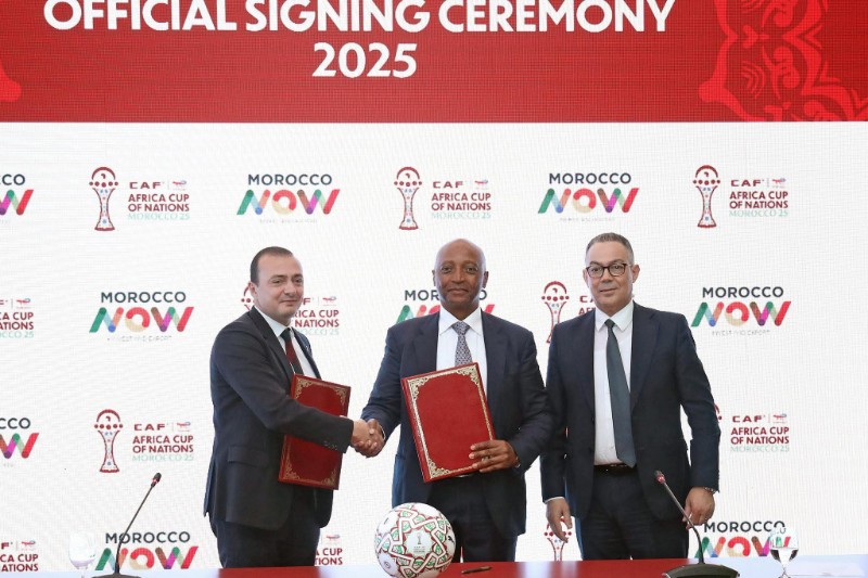 ** صورة لشعار كأس أمم إفريقيا مع علامة "Morocco Now" في الخلفية.