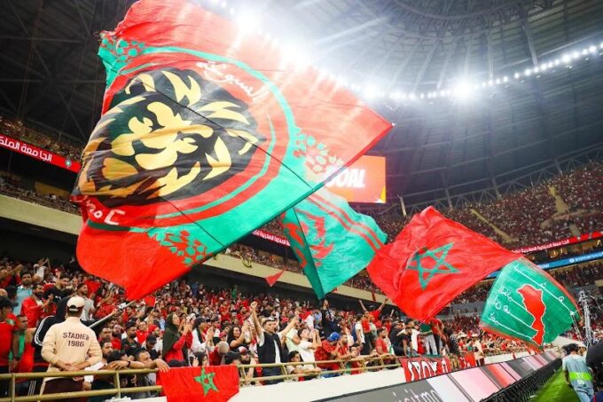 ** صورة للاعب كرة القدم يلعب مع رفاقه، مع خلفية ملونة وملونة بمعالم الرياضة الإفريقية.