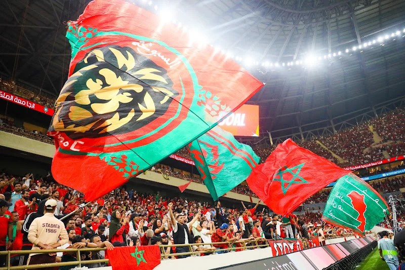 ** صورة للاعب كرة القدم يلعب مع رفاقه، مع خلفية ملونة وملونة بمعالم الرياضة الإفريقية.