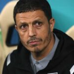 ** صورة مدرب منتخب الأردن يُشير إلى اللاعبين أثناء المؤتمر الصحفي.