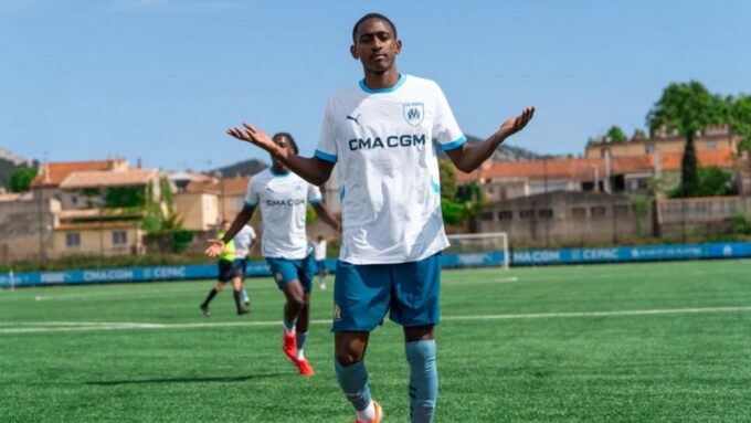 Un jeune joueur de football en action, avec le ballon dans les airs.