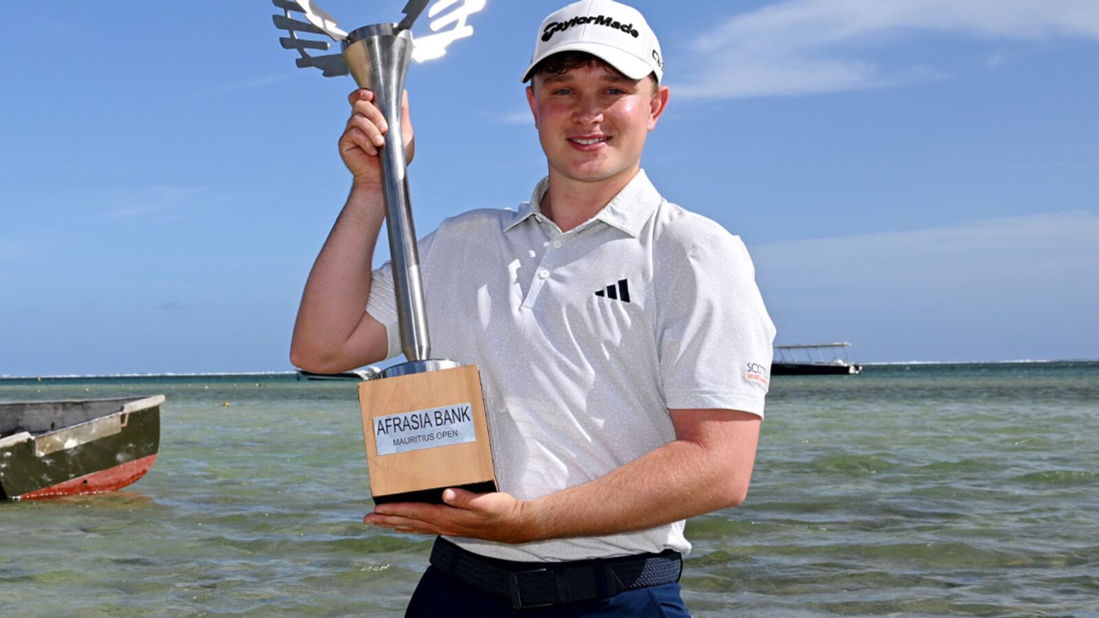 Jayden Schaper holding his trophy on the beach in Mauritius.