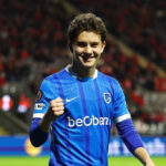 Young footballer in action, with a blurred stadium background.