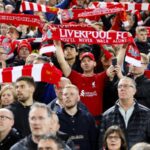 Un joueur de Liverpool en train de jouer, avec un visage grimaçant en arrière-plan. Le texte Alt pourrait être "La crise à Liverpool : une situation explosive". ###