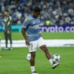 Un jeune joueur de football tenant un ballon avec un sourire.