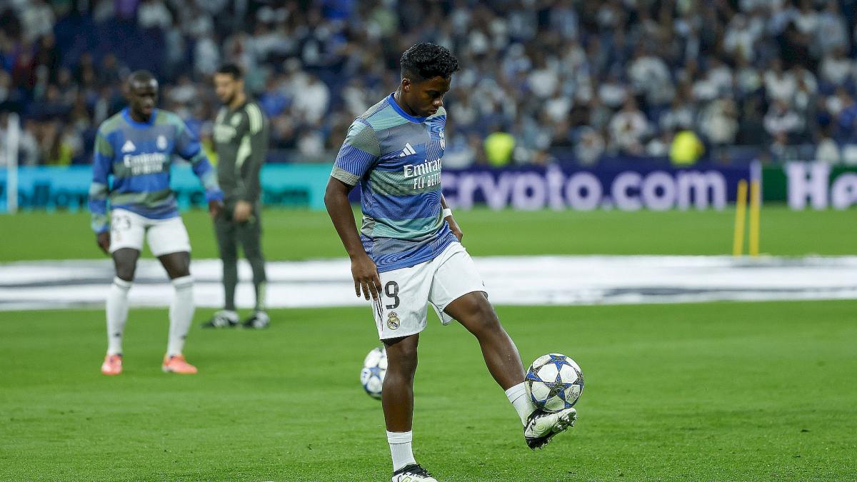 Un jeune joueur de football tenant un ballon avec un sourire.