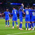 Un joueur de football en action, avec un ballon au pied, dans un stade plein de supporters.