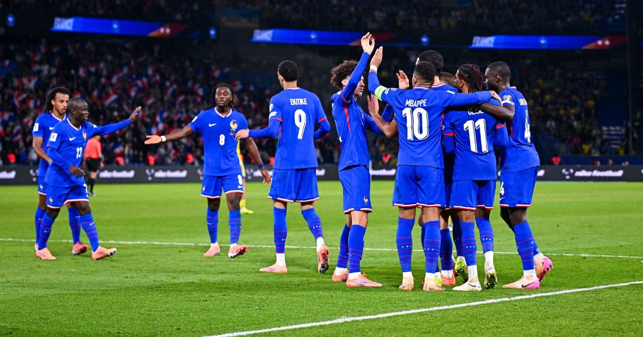 Un joueur de football en action, avec un ballon au pied, dans un stade plein de supporters.