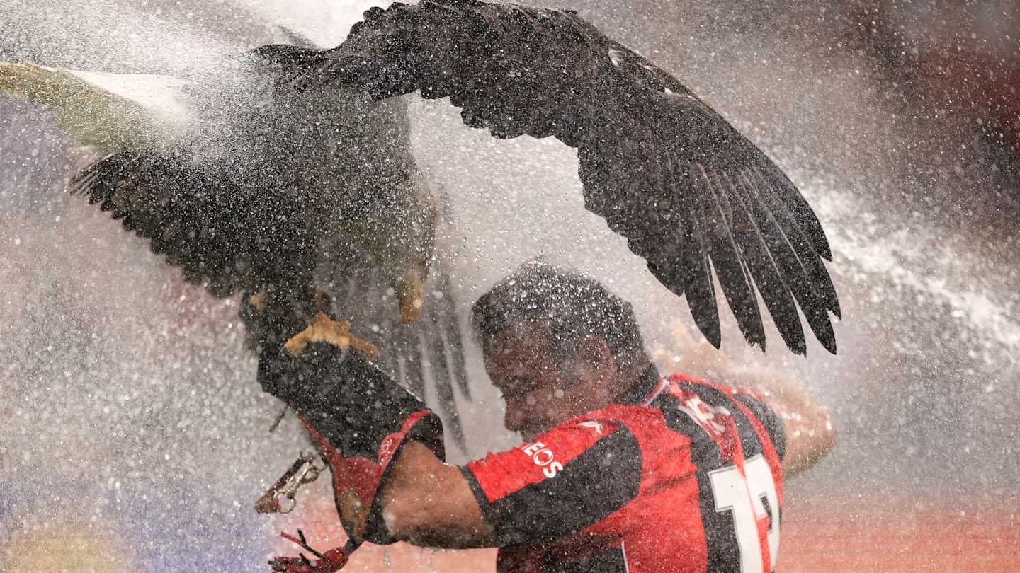 Alt text: OGC Nice's eagle mascot, Mefi, and her trainer getting drenched by a sprinkler system during a Europa League match against AS Roma.