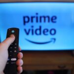 "A person holding a modified Amazon Fire Stick with a warning sign in the background."