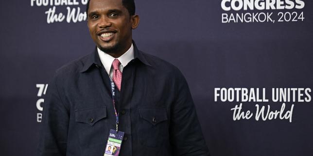 Samuel Eto'o, président de la Fecafoot, souriant devant le drapeau camerounais.