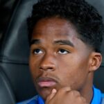 Un jeune joueur de football avec un ballon et un maillot de l'Olympique Lyonnais.