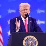 Le président américain Donald Trump s'exprimant, avec le drapeau américain en arrière-plan.