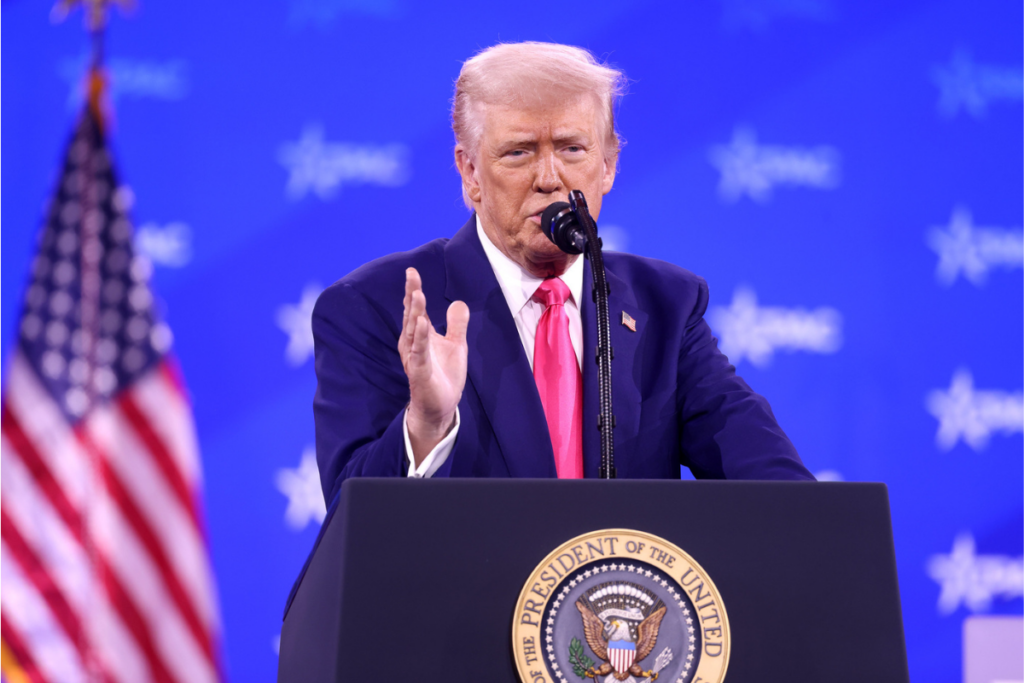 Le président américain Donald Trump s'exprimant, avec le drapeau américain en arrière-plan.