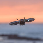 Drone DJI Neo 2 ultra-compact avec hélices protégées, en vol ou posé, illustrant sa petite taille et sa robustesse.