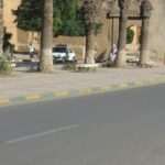 Panneau d'école sous une pluie battante à Taroudant, avec des nuages sombres en arrière-plan.